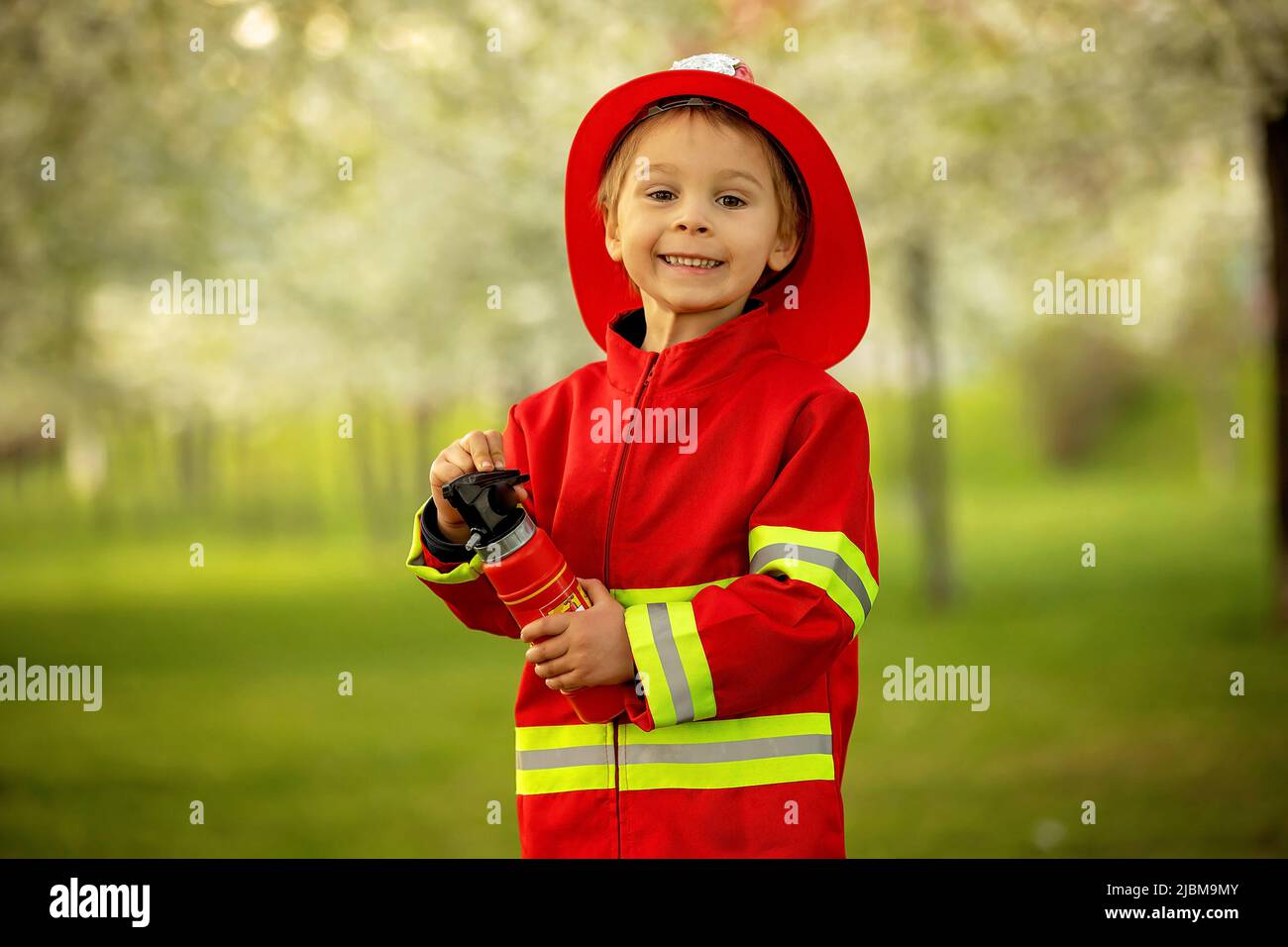 Petit enfant avec costume de pompier dans le parc, prétendant être un vrai pompier, jouant au coucher du soleil Banque D'Images