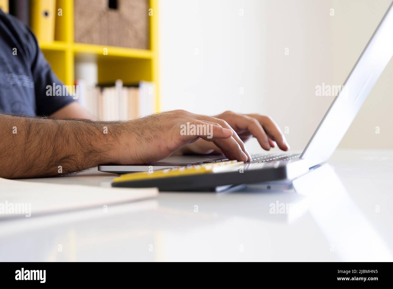 À l'aide d'un ordinateur portable et d'une calculatrice, gros plan des mains à l'aide d'un ordinateur portable et d'une calculatrice. Homme d'affaires travaille sur un projet, en tapant sur le clavier des ordinateurs portables. Banque D'Images