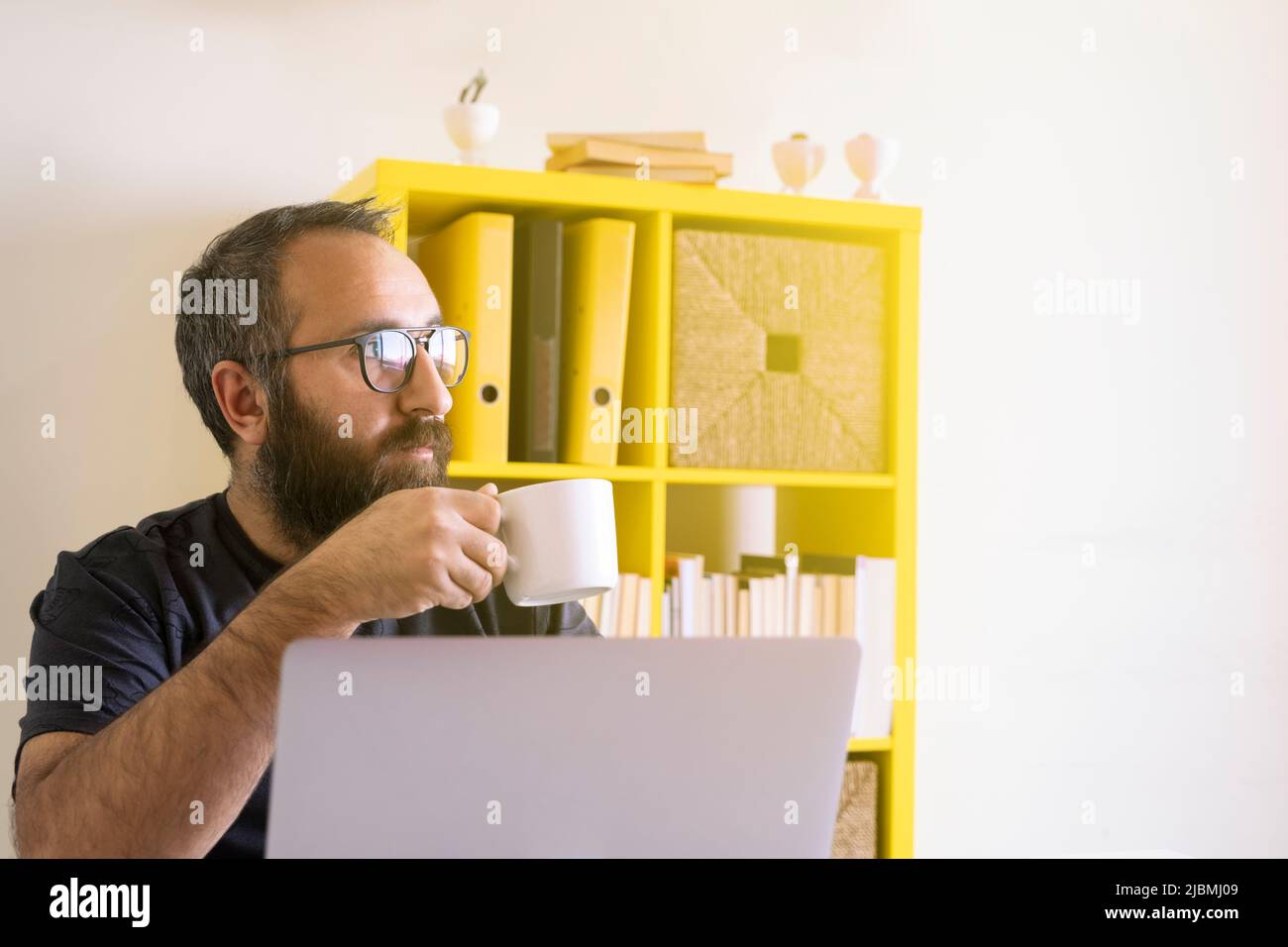 Dégustez un café frais, un homme d'affaires hippster millénaire du Caucase qui apprécie un café frais. Employé de bureau ou employé travaillant et buvant une boisson chaude. Banque D'Images