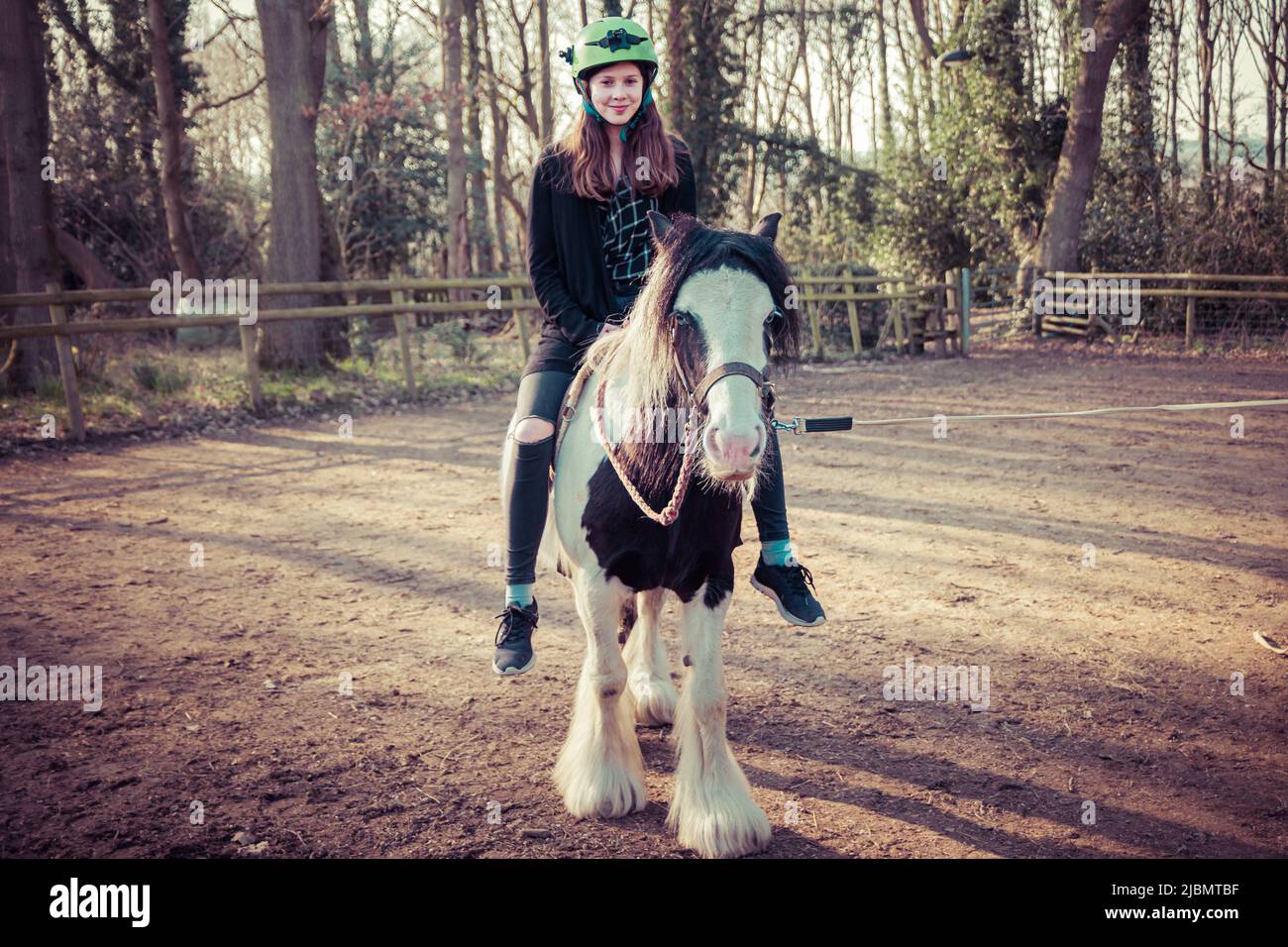 Une adolescente assise sur un poney piébald gitan en épi Banque D'Images