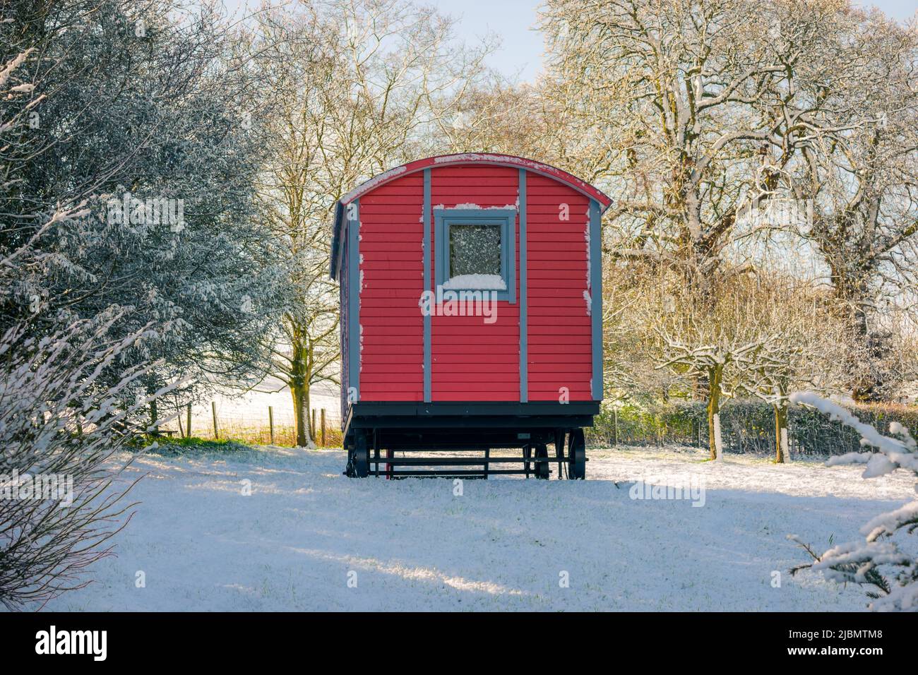 Magnifique cabane de berger rouge vintage ou chariot de derrière dans une scène de neige de printemps Banque D'Images