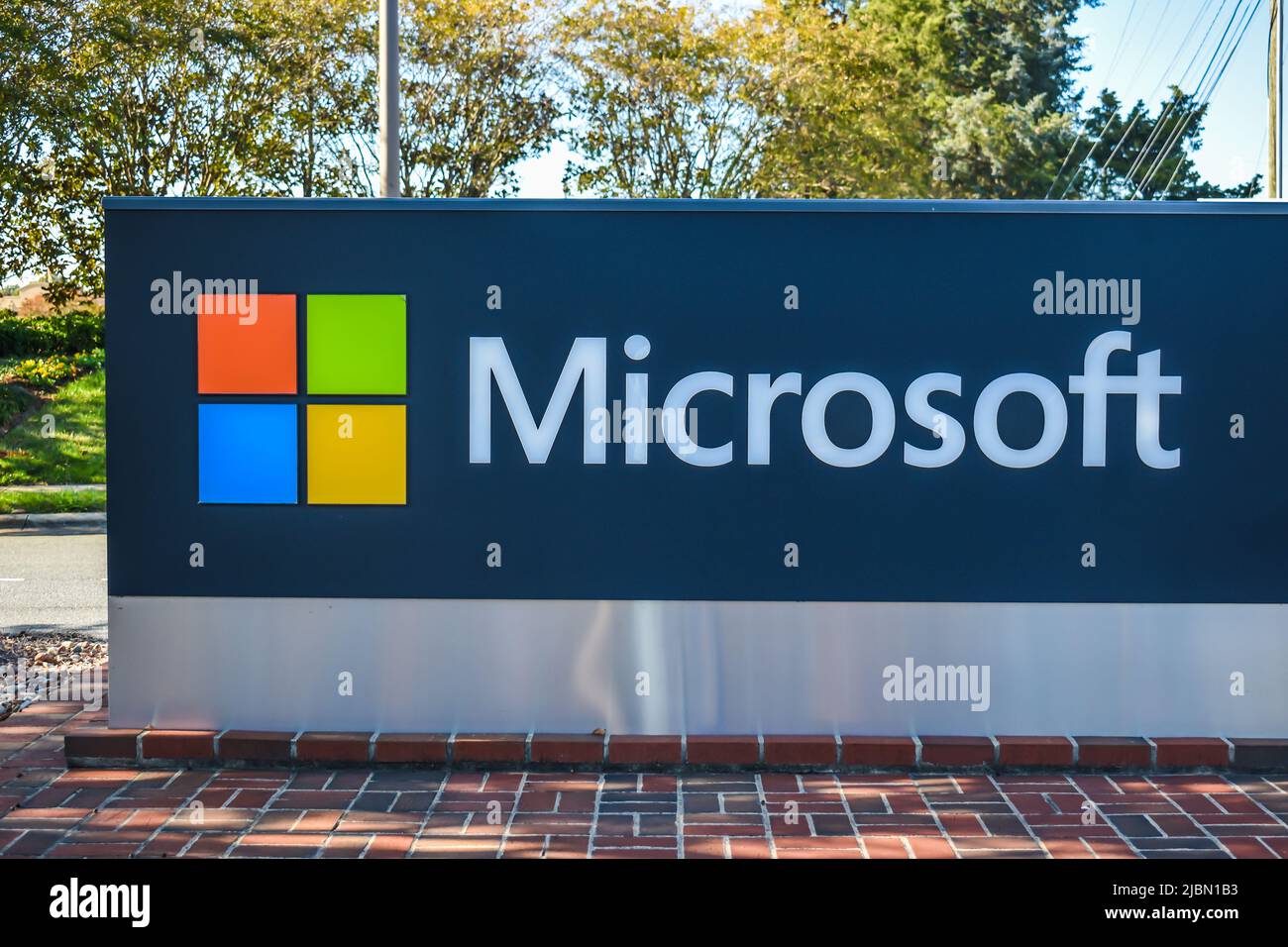 Microsoft Free debout marque et logo coloré publicité en plein air dans la lumière ombragée avec des arbres verts et le ciel dans l'arrière-plan. Banque D'Images