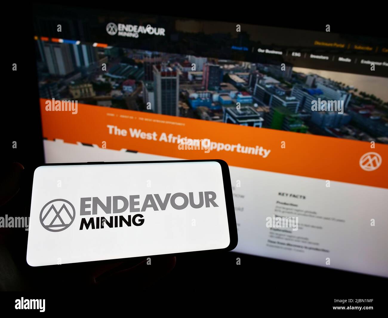 Personne détenant un smartphone avec le logo de la société d'exploration aurifère Endeavour Mining plc sur l'écran devant le site Web. Mise au point sur l'affichage du téléphone. Banque D'Images