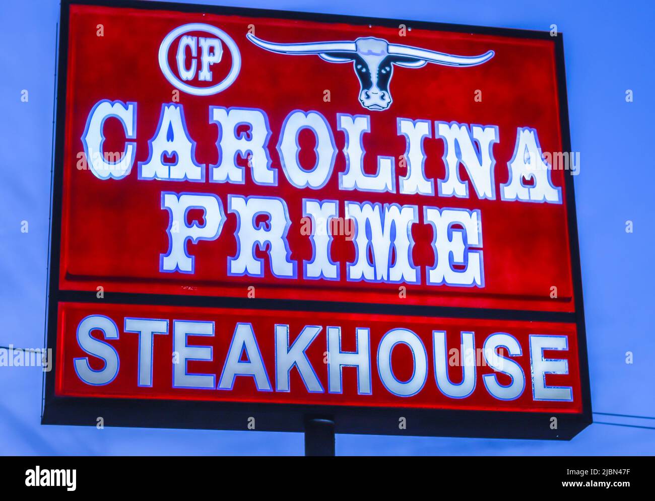 Carolina Prime Steakhouse extérieur, publicité de rue libre éclairée en lettres blanches sur fond rouge contre un ciel bleu. Banque D'Images