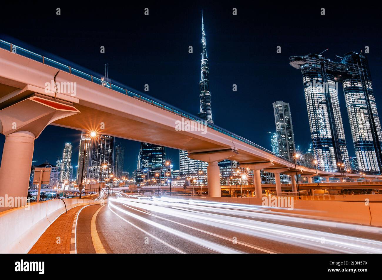 Dubaï, Émirats arabes Unis : métro et voitures rapides la nuit dans le centre-ville de Dubaï avec le plus haut bâtiment du monde, le Burj Khalifa, en arrière-plan. Banque D'Images
