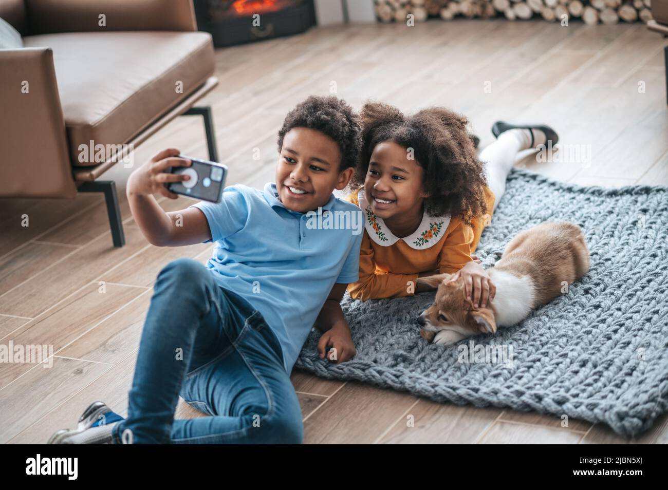 Un garçon en tshirt bleu faisant le selfie avec sa sœur et un chien Banque D'Images