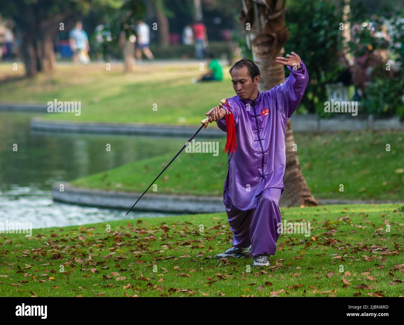 Homme thaïlandais mature effectuant des exercices de Tai Chi avec une longue épée à lame dans le parc Lumpini, Bangkok, Thaïlande Banque D'Images