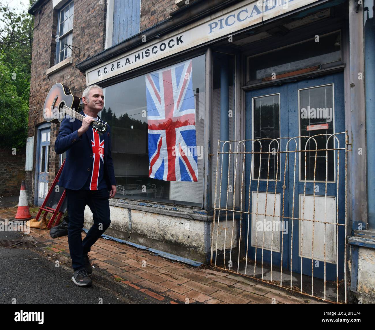 Les drapeaux sont toujours là, mais la fête du Jubilé de platine de la Reine est terminée et c'est une courte promenade à pied pour le musicien Neil Gray après avoir divertissant le villageois Banque D'Images