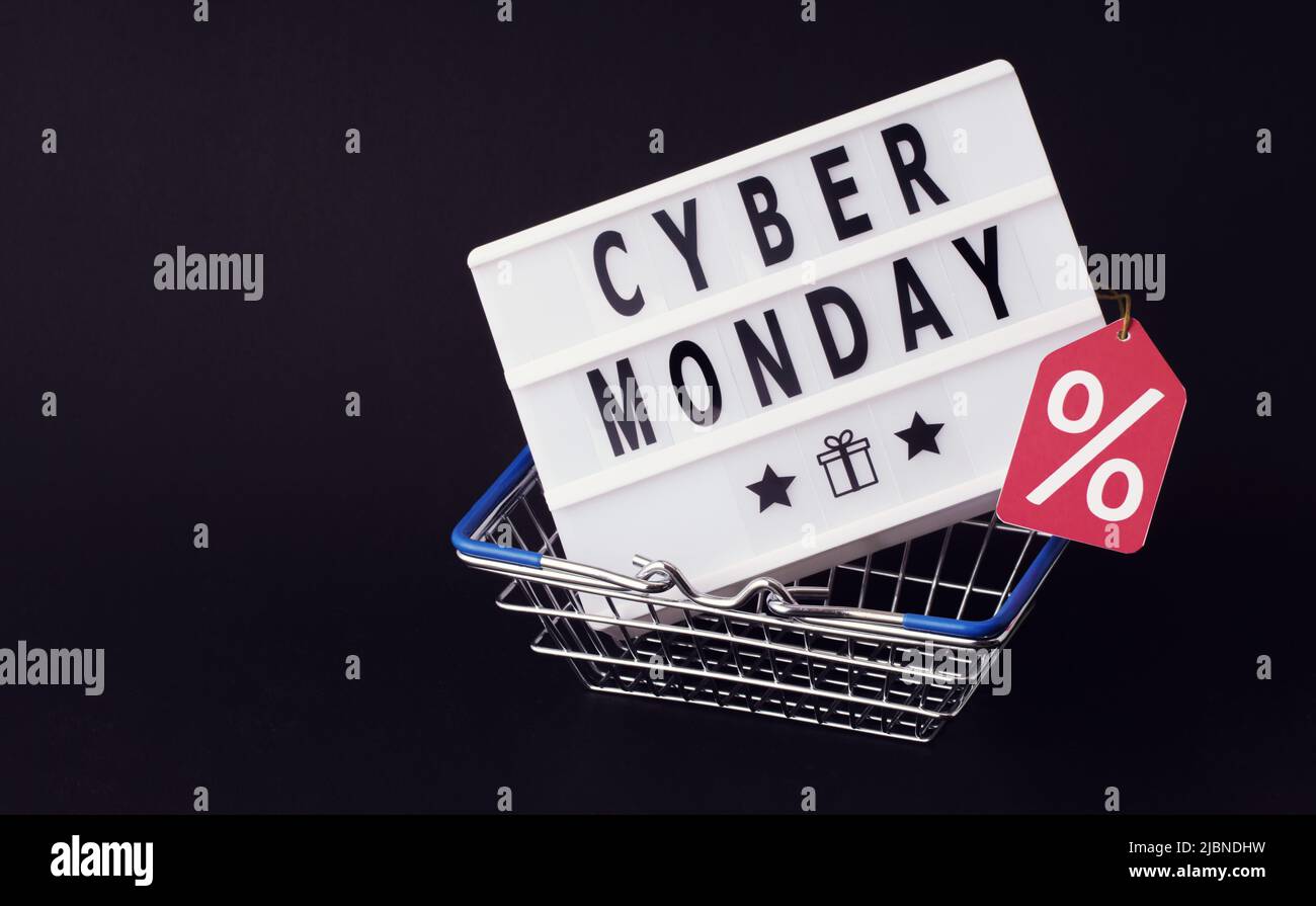 Cyber monday orthographié dans des lettres sur la boîte claire dans le panier d'achat, le concept de vendredi noir sur fond sombre Banque D'Images