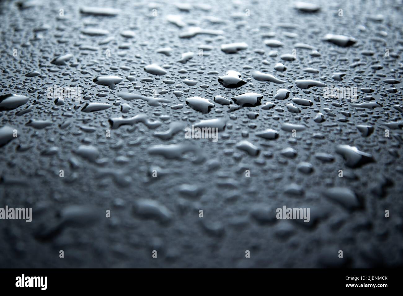 vaporiser des gouttelettes d'eau sur une surface métallique noire Banque D'Images