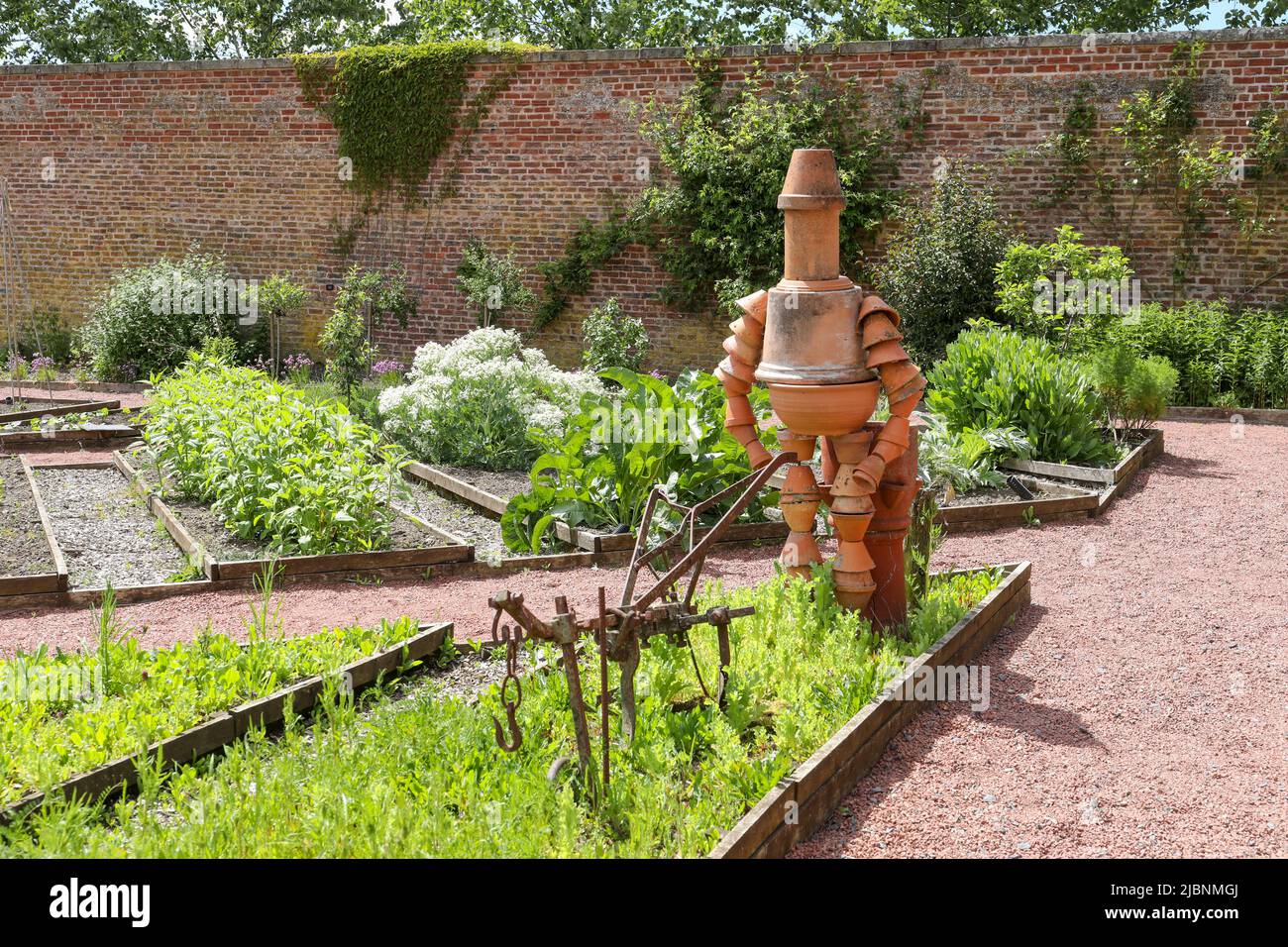 Statue en terre cuite d'un homme travaillant dans le jardin avec une vieille charrue en fer forgé, jardin clos, Dumfries House, Cumnock, Ayrshire, Écosse, Royaume-Uni Banque D'Images