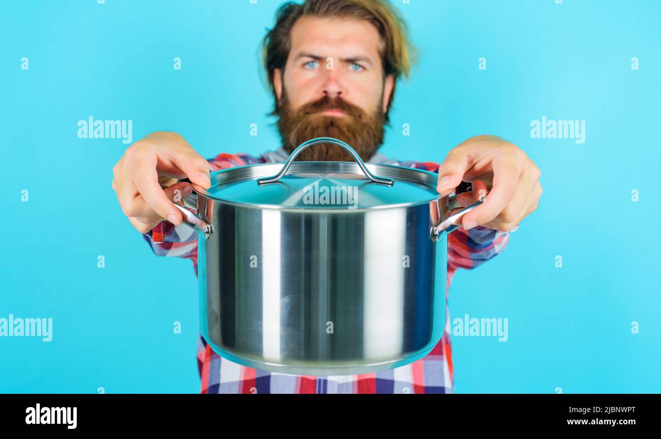 Homme barbu avec une casserole ou un pot. Préparation des aliments. Ustensiles de cuisine. Publicité sur les ustensiles de cuisine. Banque D'Images