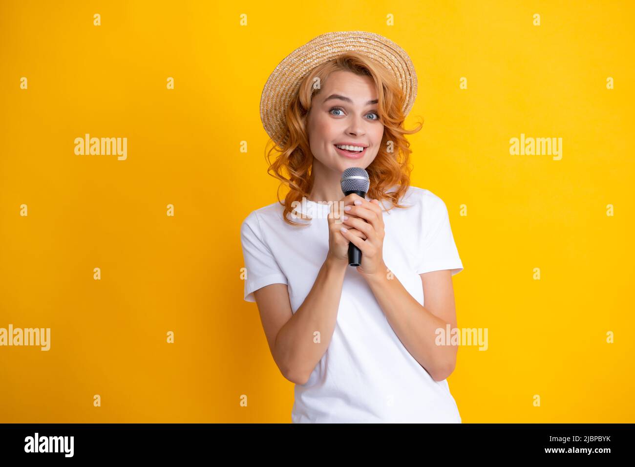 Belle jeune femme chantant karaoké isolée sur jaune. Fille chantant la bande sonore au micro. Banque D'Images