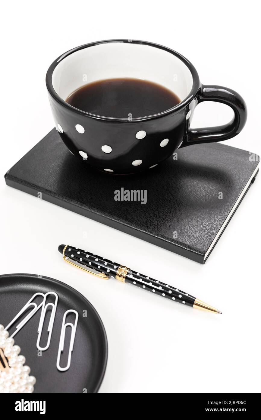 Espace de travail noir et blanc avec un mug à pois et un cahier Banque D'Images