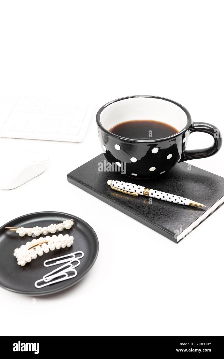 Espace de travail noir et blanc avec un mug à pois et un cahier Banque D'Images