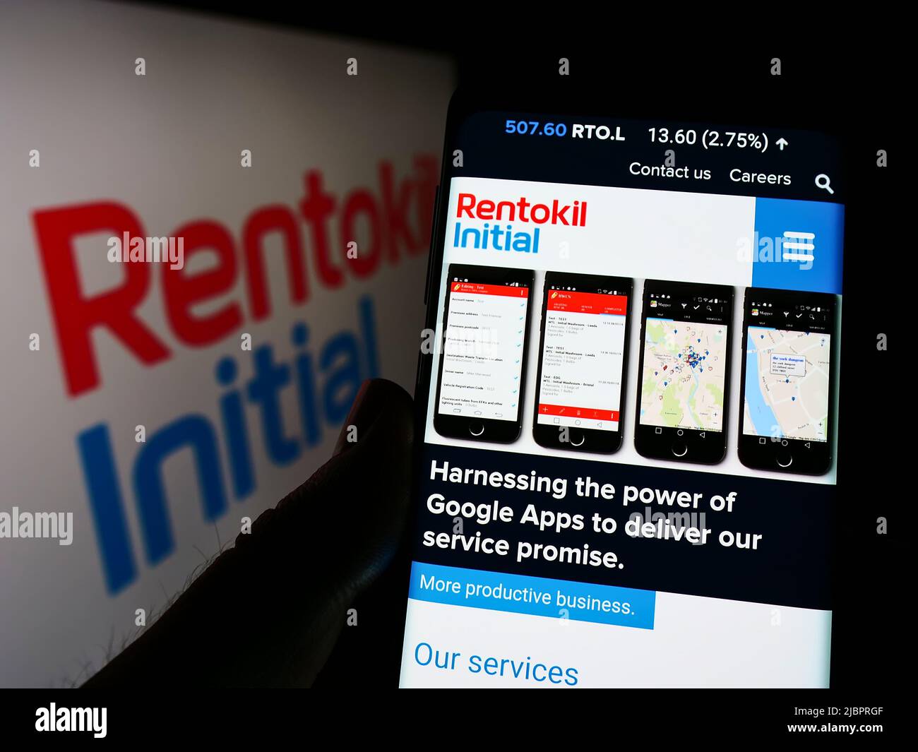 Personne tenant un téléphone portable avec la page web de la société britannique de services Rentokil initial plc à l'écran avec logo. Concentrez-vous sur le centre de l'écran du téléphone. Banque D'Images