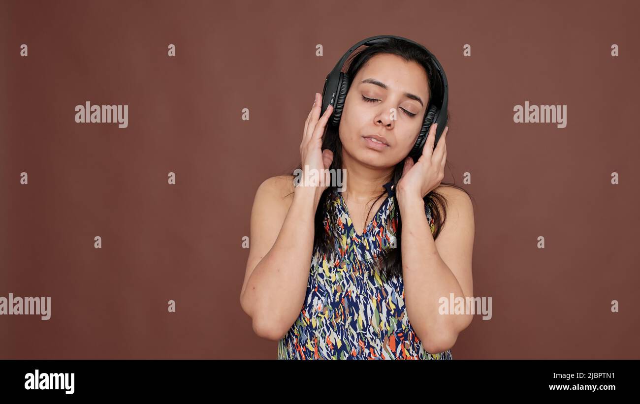 Femme indienne qui s'amuse à écouter de la musique sur un casque, en  utilisant la radio mp3 pour écouter des chansons audio. Danse sur le rythme  sonore et la mélodie pour le