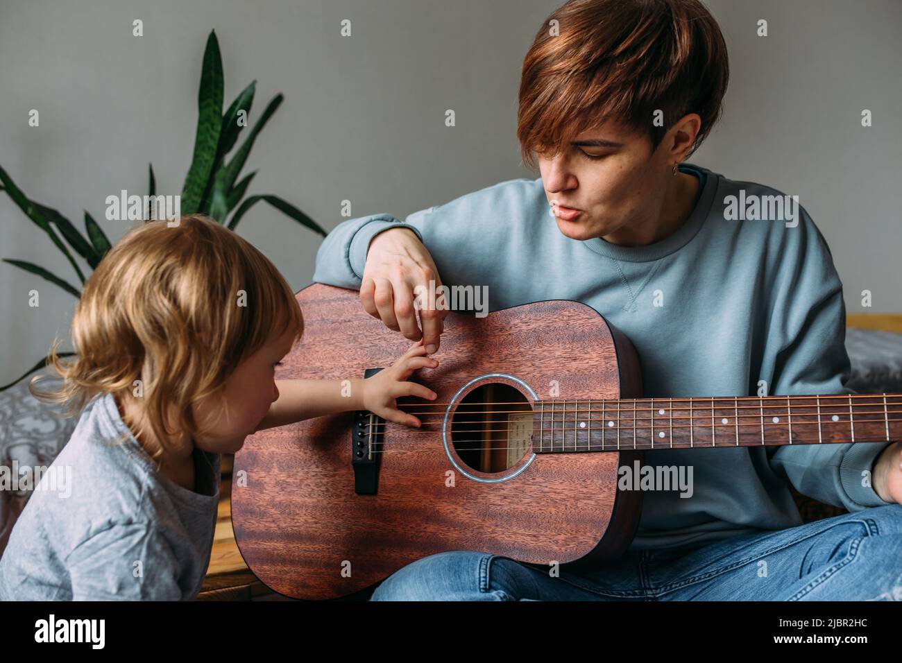 Une petite fille joue de la guitare avec sa mère sur le sol à la maison Banque D'Images