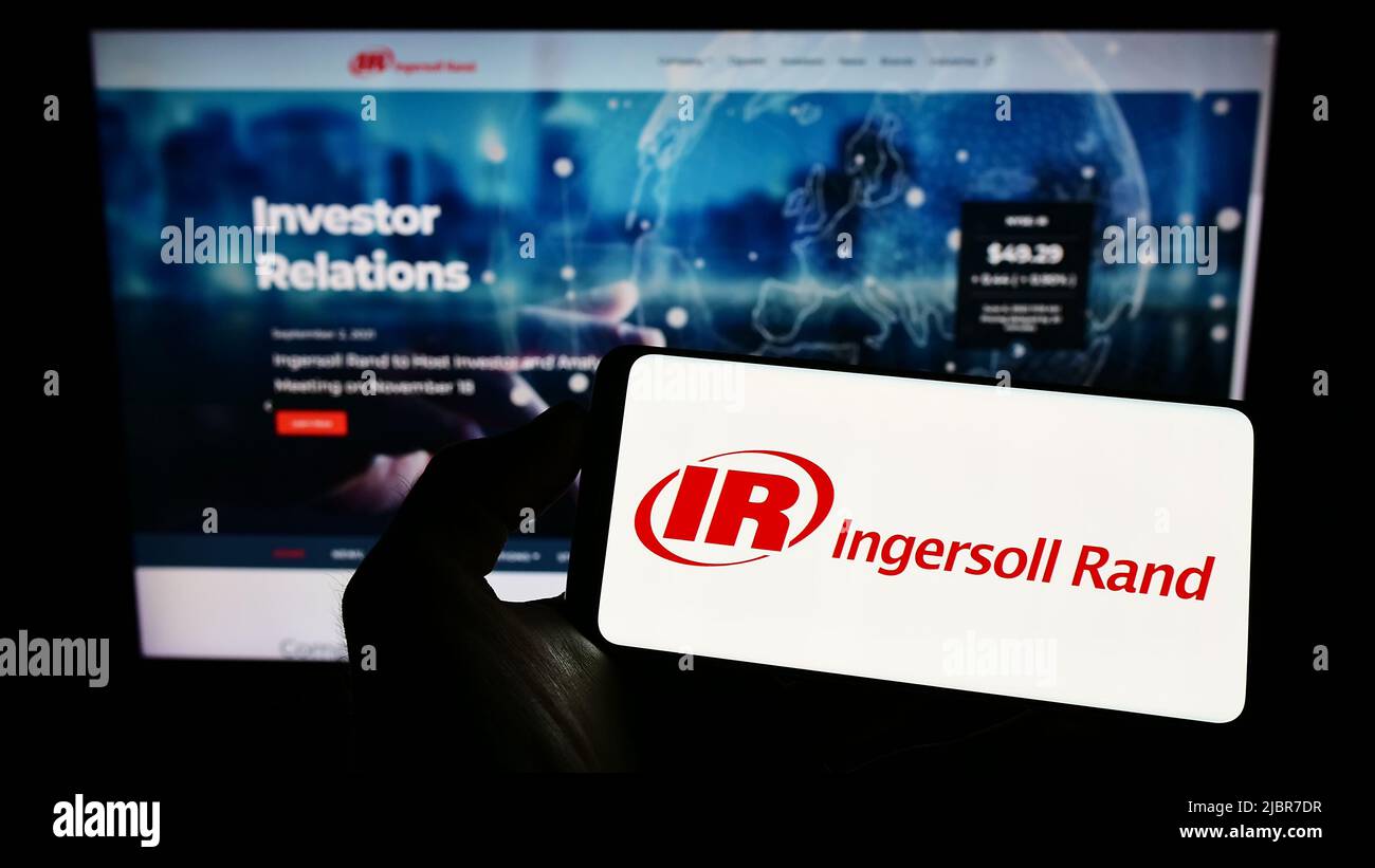 Personne tenant un téléphone portable avec le logo de la société américaine de machines Ingersoll Rand Inc. (IR) à l'écran en face de la page Web. Mise au point sur l'affichage du téléphone. Banque D'Images