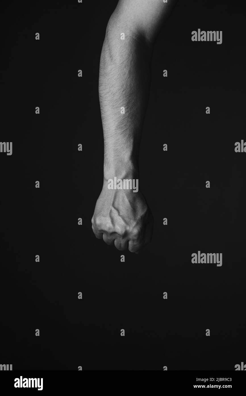 Main brutale des mans avec des veines saillantes, fond noir.photo noire et blanche. Banque D'Images