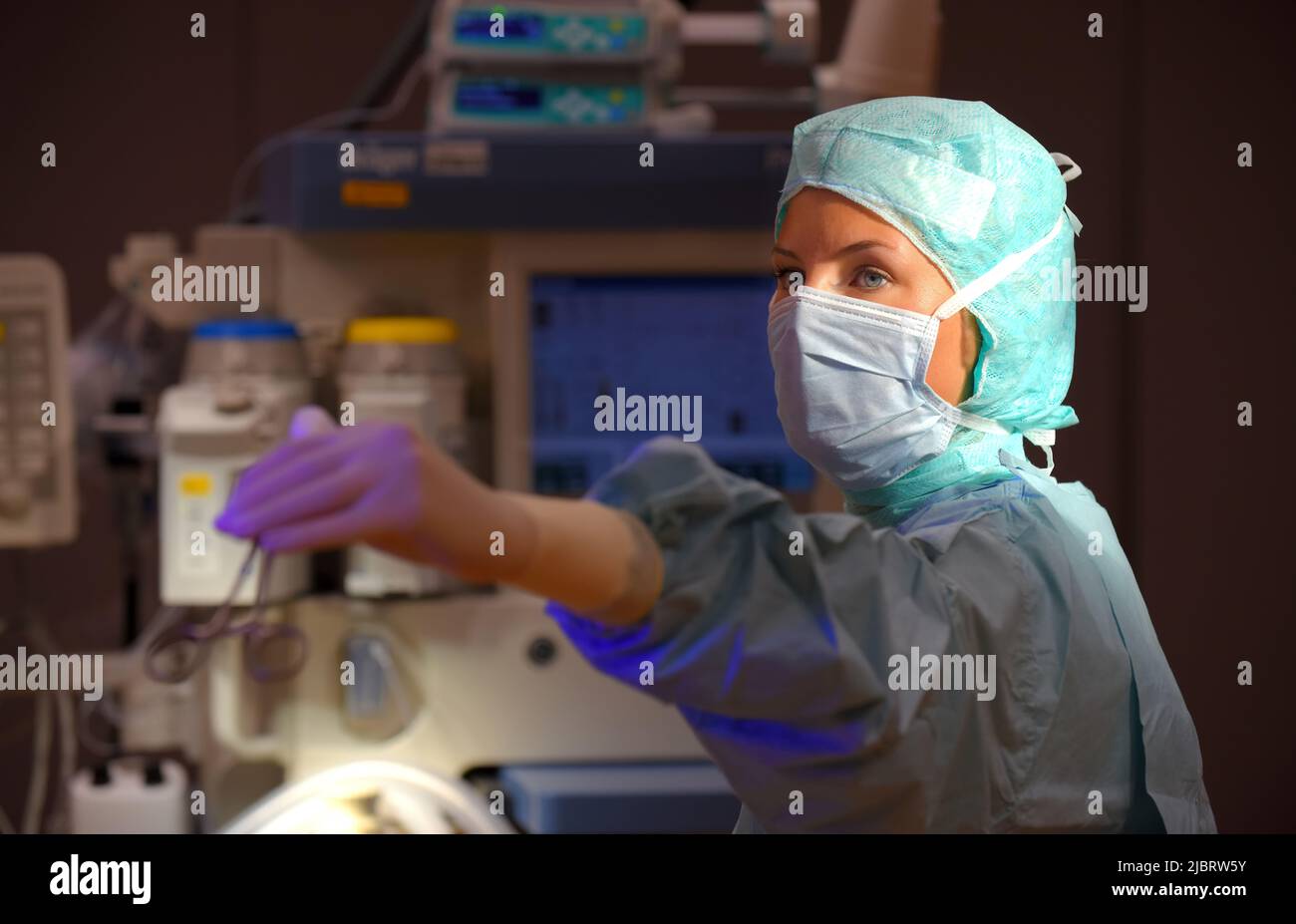 Une femme est vue dans un théâtre d'opération de l'hôpital. Elle est entièrement habillée comme infirmière anesthésique avec un masque facial et des vêtements chirurgicaux médicaux stériles. Banque D'Images