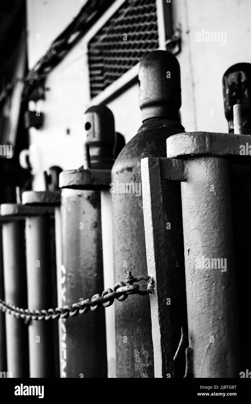 Bouteilles de gaz comprimé stockées verticalement fixées par une chaîne métallique. Banque D'Images