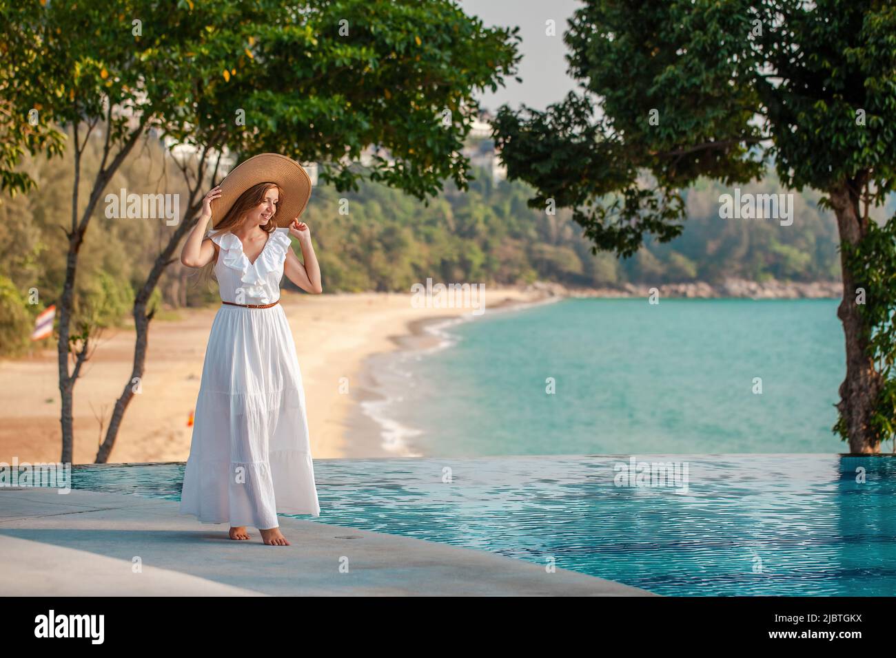 Jeune femme marchant près de la piscine avec vue sur la mer dans un complexe tropical moderne Banque D'Images