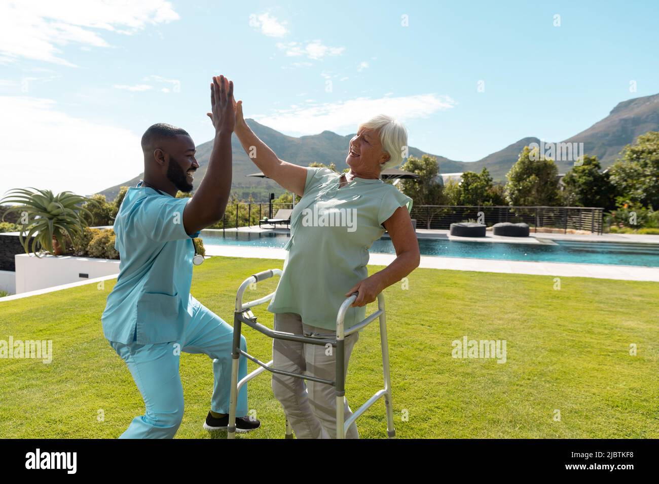 Afro-américain travailleur de la santé et caucasienne femme âgée de haut fiving les uns les autres dans le jardin Banque D'Images