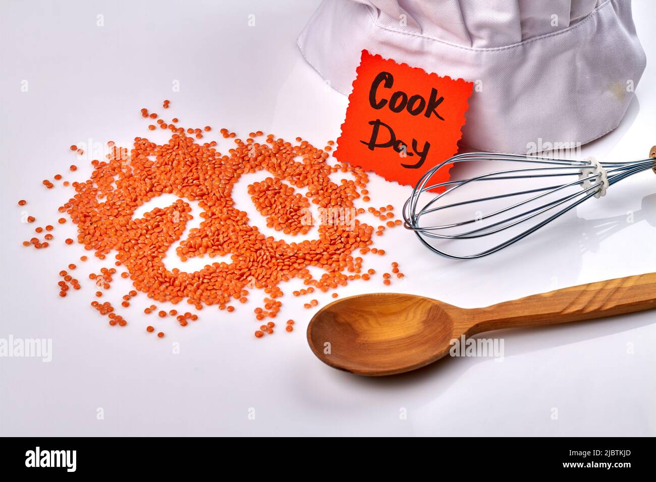 Concept de la journée de cuisson. Pile de lentilles en forme de numéro 20. Cuillère en bois et outil mélangeur sur fond blanc. Banque D'Images
