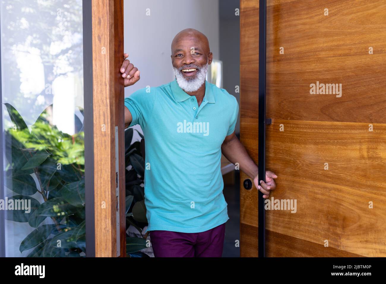 Portrait d'un homme senior afro-américain joyeux accueillant debout à la porte dans une maison de retraite Banque D'Images