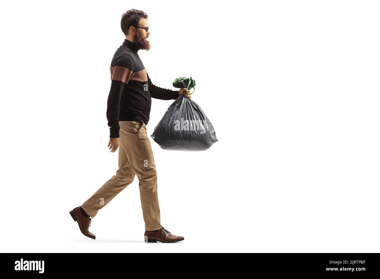 Photo pleine longueur d'un homme barbu marchant et portant un sac de déchets en plastique isolé sur fond blanc Banque D'Images