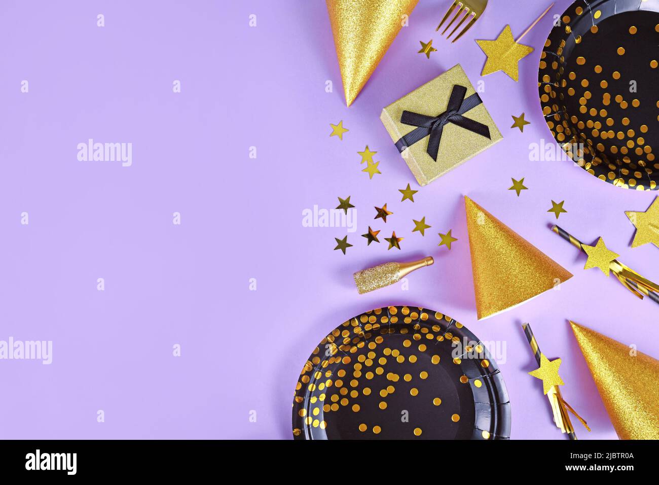 Plat de fête avec assiettes noires et dorées, fourchettes, cadeau, bouteille de champagne et confetti aux étoiles sur fond violet avec espace de copie Banque D'Images Plat de fête avec assiettes noires et dorées, fourchettes, cadeau, bouteille de champagne et confetti aux étoiles sur fond violet avec espace de copie Banque D'Images