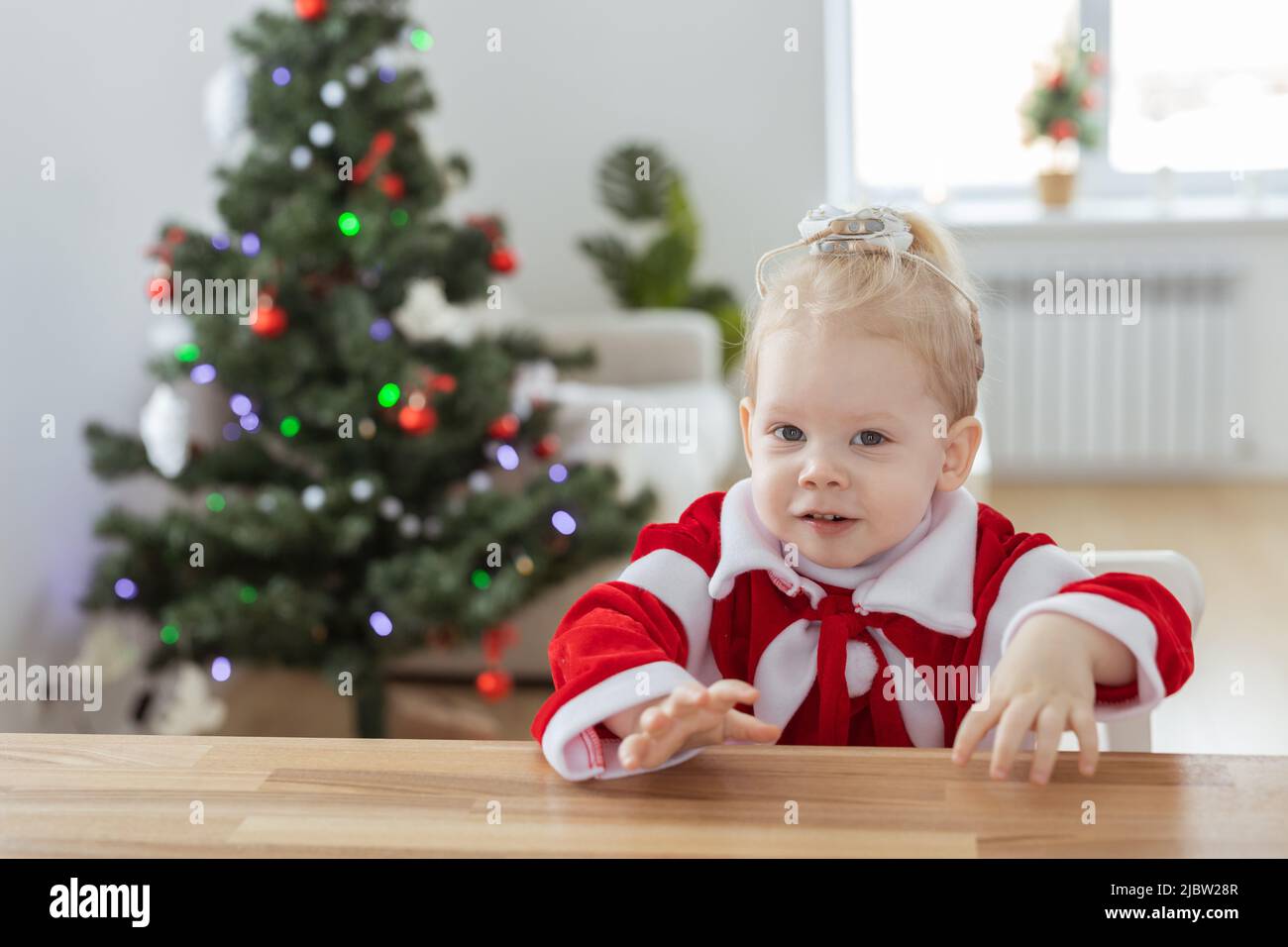 Enfant fille vêtue d'une robe de noël avec implants cochléaires s'amusant à la maison - diversité et aide auditive et technologies innovantes pour le traitement Banque D'Images