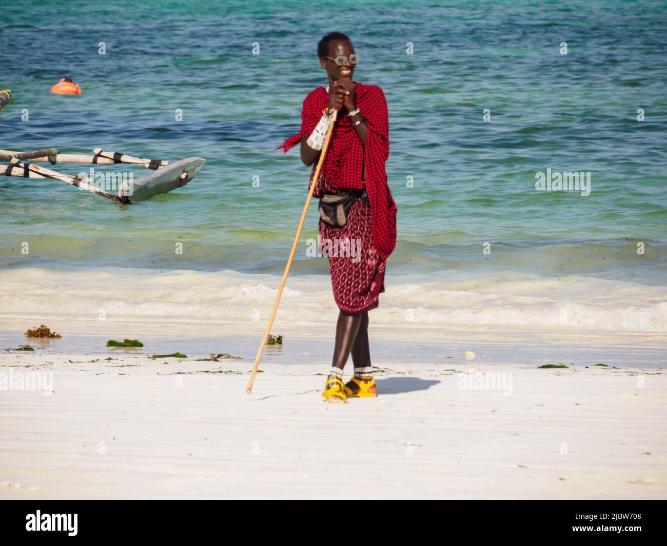 Zanzibar, Tanzanie - janvier 2021: Guerrier Maasai africain en robe traditionnelle sur une plage de sable. Afrique Banque D'Images Zanzibar, Tanzanie - janvier 2021: Guerrier Maasai africain en robe traditionnelle sur une plage de sable. Afrique Banque D'Images
