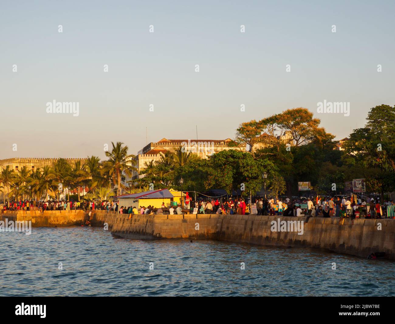 Ville de pierre, Zanzibar, Tanzanie - Jan 2021: Foule des gens sur les jardins de Forodhani et les enfants sautant dans l'eau d'un mur pendant l'heure du coucher du soleil. C Banque D'Images