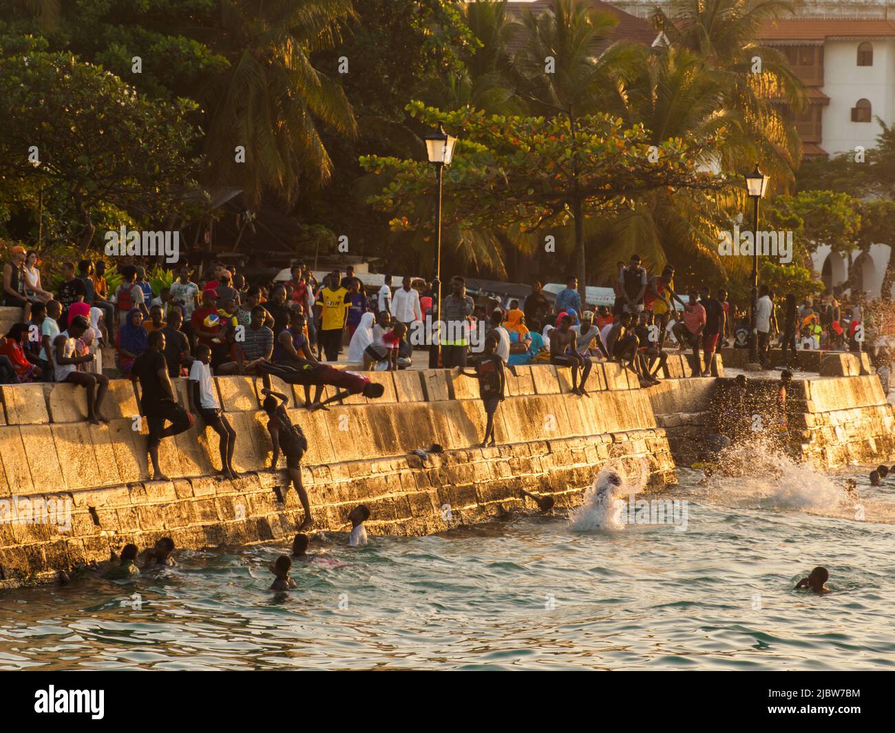 Ville de pierre, Zanzibar, Tanzanie - Jan 2021: Foule des gens sur les jardins de Forodhani et les enfants sautant dans l'eau d'un mur pendant l'heure du coucher du soleil. C Banque D'Images