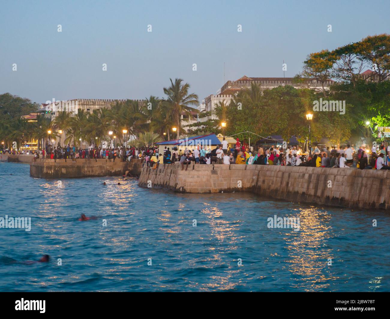 Ville de pierre, Zanzibar, Tanzanie - Jan 2021: Foule des gens sur les jardins de Forodhani et les enfants sautant dans l'eau d'un mur pendant la soirée TI Banque D'Images