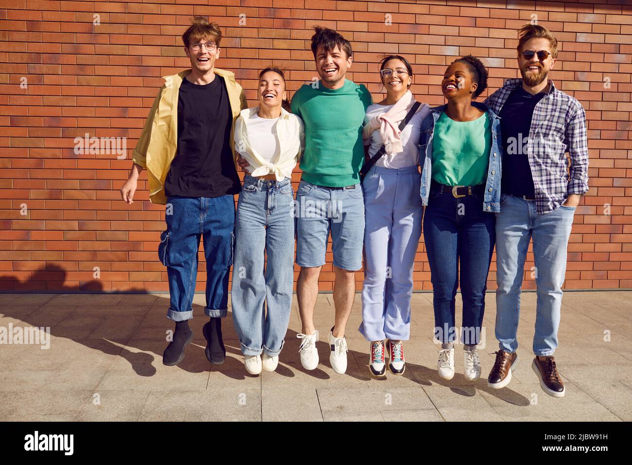 Un groupe d'amis joyeux et joyeux se rencontrent dans les rues de la ville et s'amusent ensemble Banque D'Images