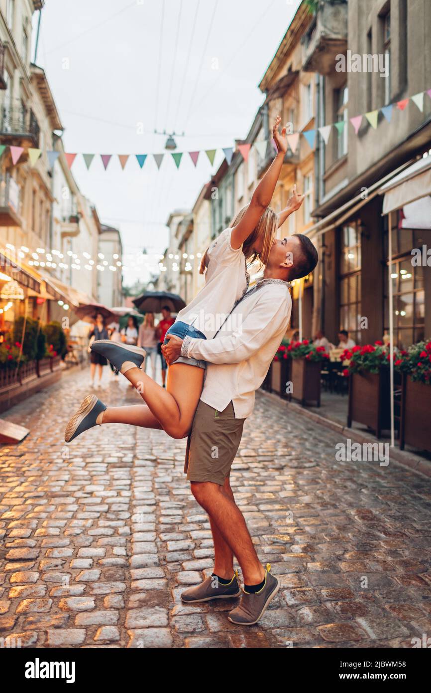 Couple amoureux marchant dans la vieille ville de Lviv portant des chemises ukrainiennes traditionnelles. Homme élevant la femme, embrassant et s'amusant à l'extérieur dans la rue Banque D'Images