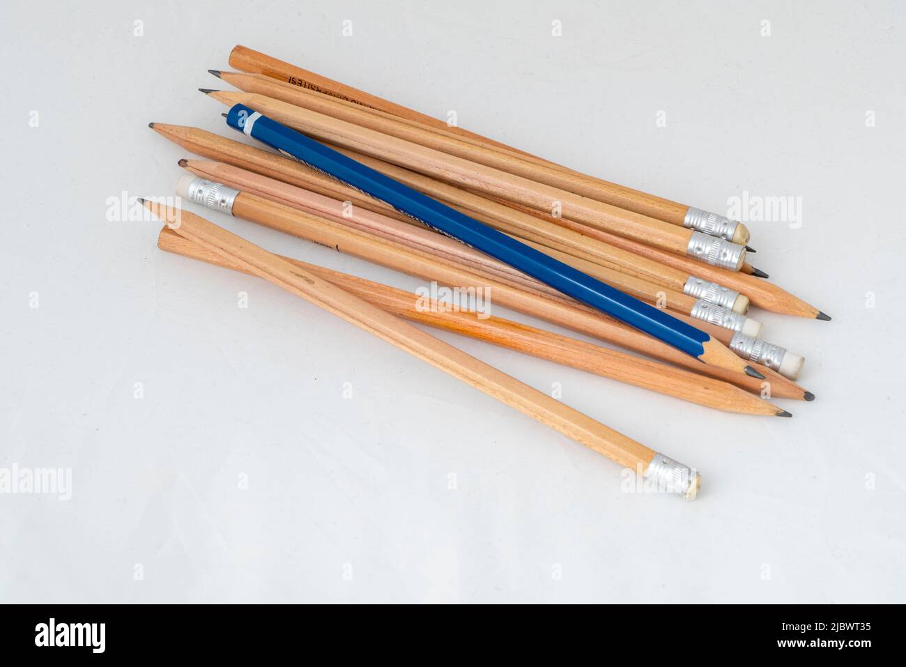 Un crayon bleu solitaire parmi des crayons en bois. Banque D'Images