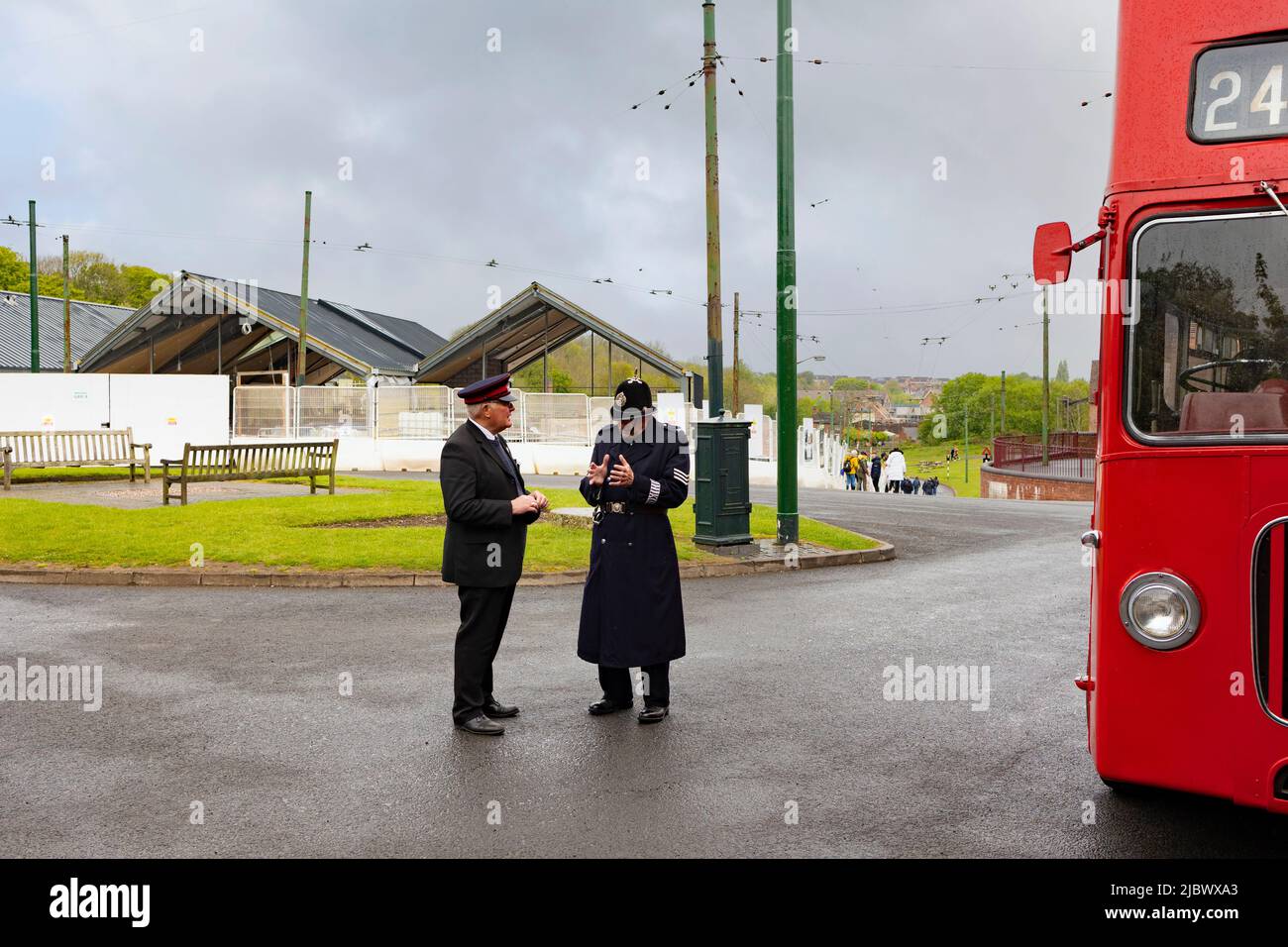 Dudley, West Midlands-royaume-uni 01 mai 2022 deux hommes parlant l'un un un conducteur d'autobus autre un policier dans les années 1940 vêtements à côté d'un double decker rouge Banque D'Images