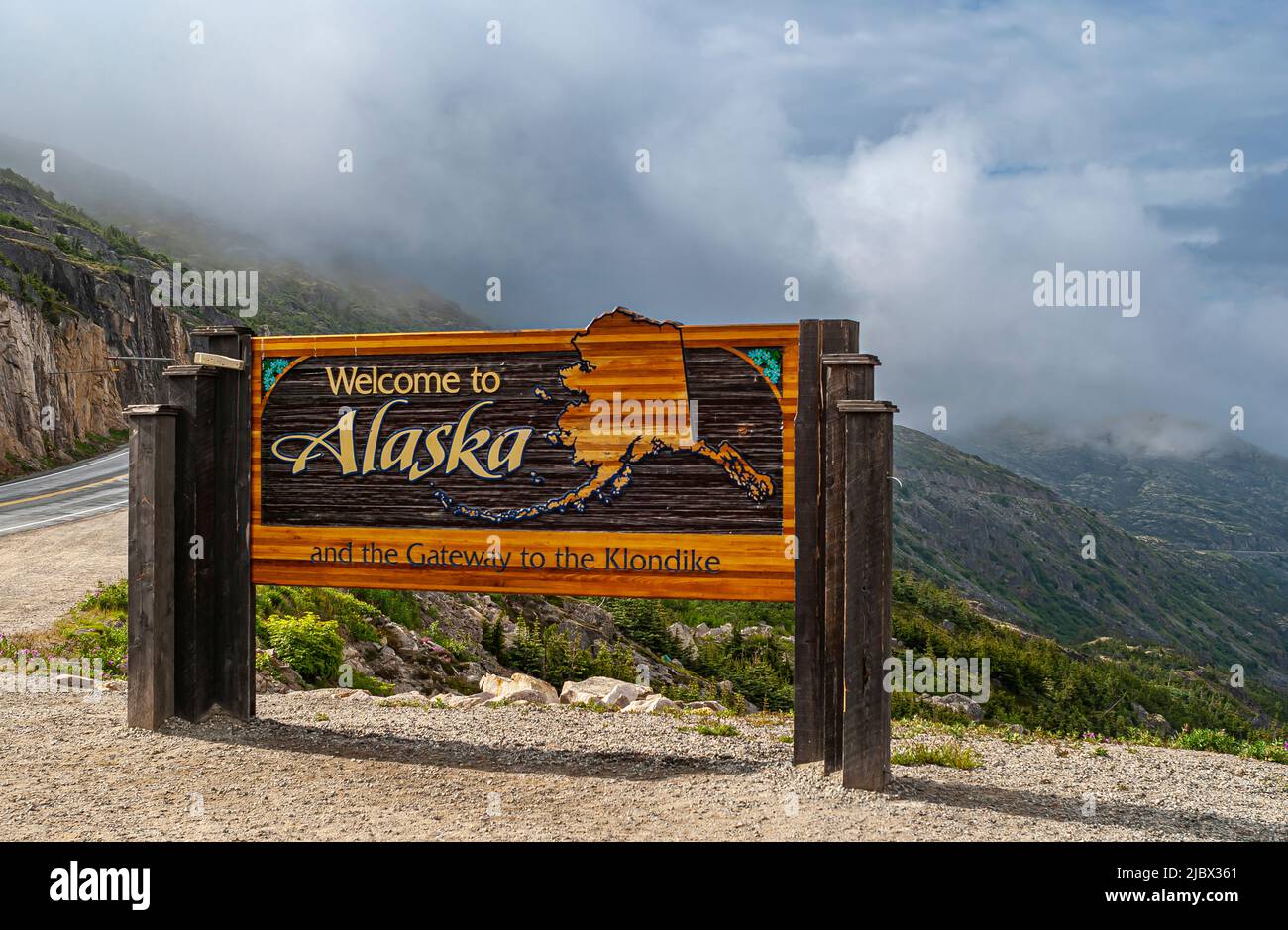 Skagway, Alaska, États-Unis - 20 juillet 2011 : route du Klondike vers le Canada. Panneau d'accueil coloré près de la frontière. Cloudscape à l'arrière. Banque D'Images