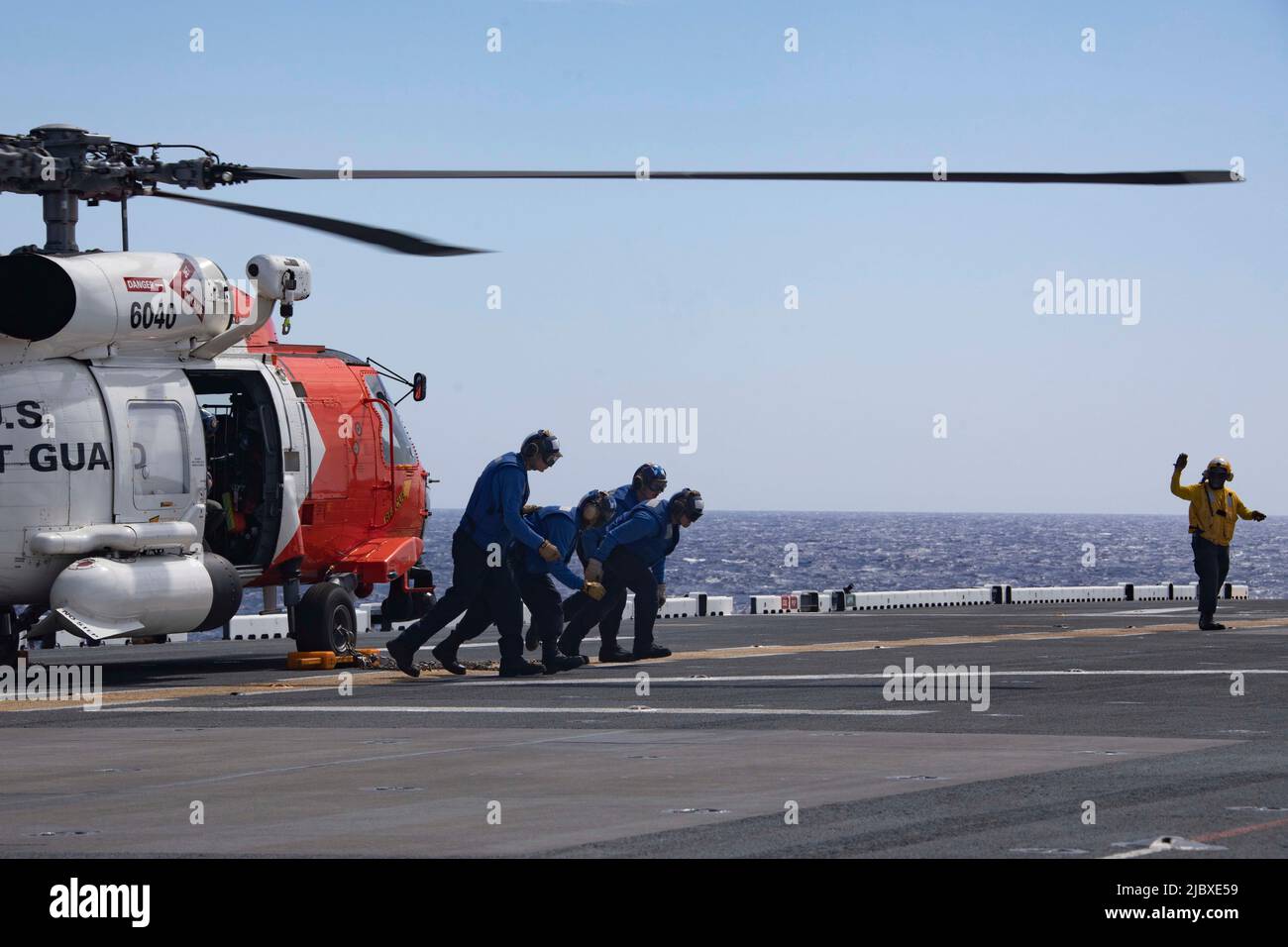 220606-N-MH210-1003 OCÉAN ATLANTIQUE (6 juin 2022) - des marins affectés au navire d'assaut amphibie USS Bataan (LHD 5) traversent le pont de vol après avoir arrié un hélicoptère MH-60 de la Garde côtière américaine 6 juin 2022. Bataan opère dans la zone de responsabilité de la flotte 2nd. Bataan est à la base navale de Norfolk. (É.-U. Photo de la marine par le Spécialiste des communications de masse 1st classe Zachary A. Anderson) Banque D'Images