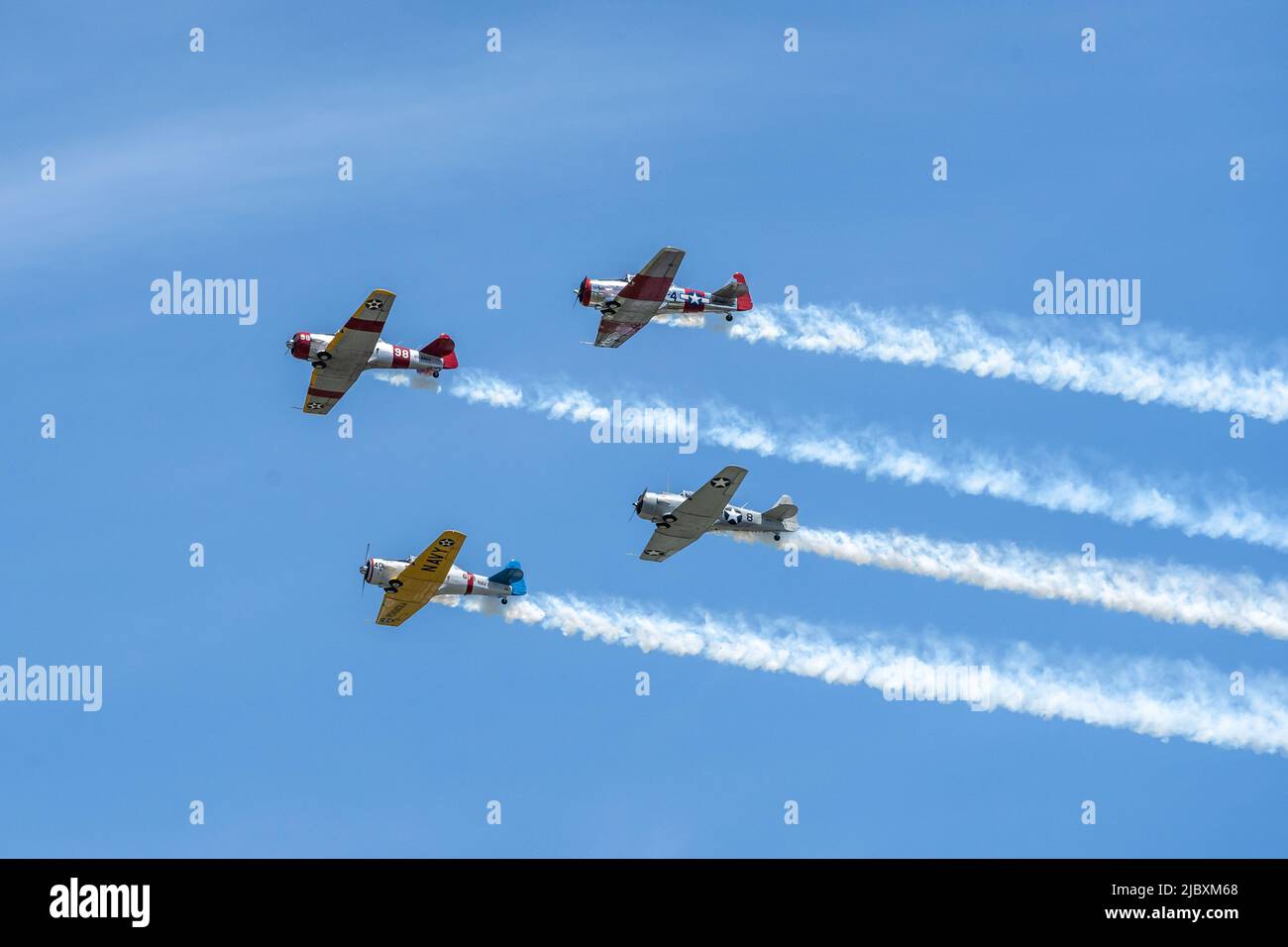 Reading, Pennsylvania, USA-6 juin 2022: Quatre avions de la Seconde Guerre mondiale de la fumée de fuite faire un survol contre un fond bleu ciel pendant le Mid-Atlantic Museum WW Banque D'Images