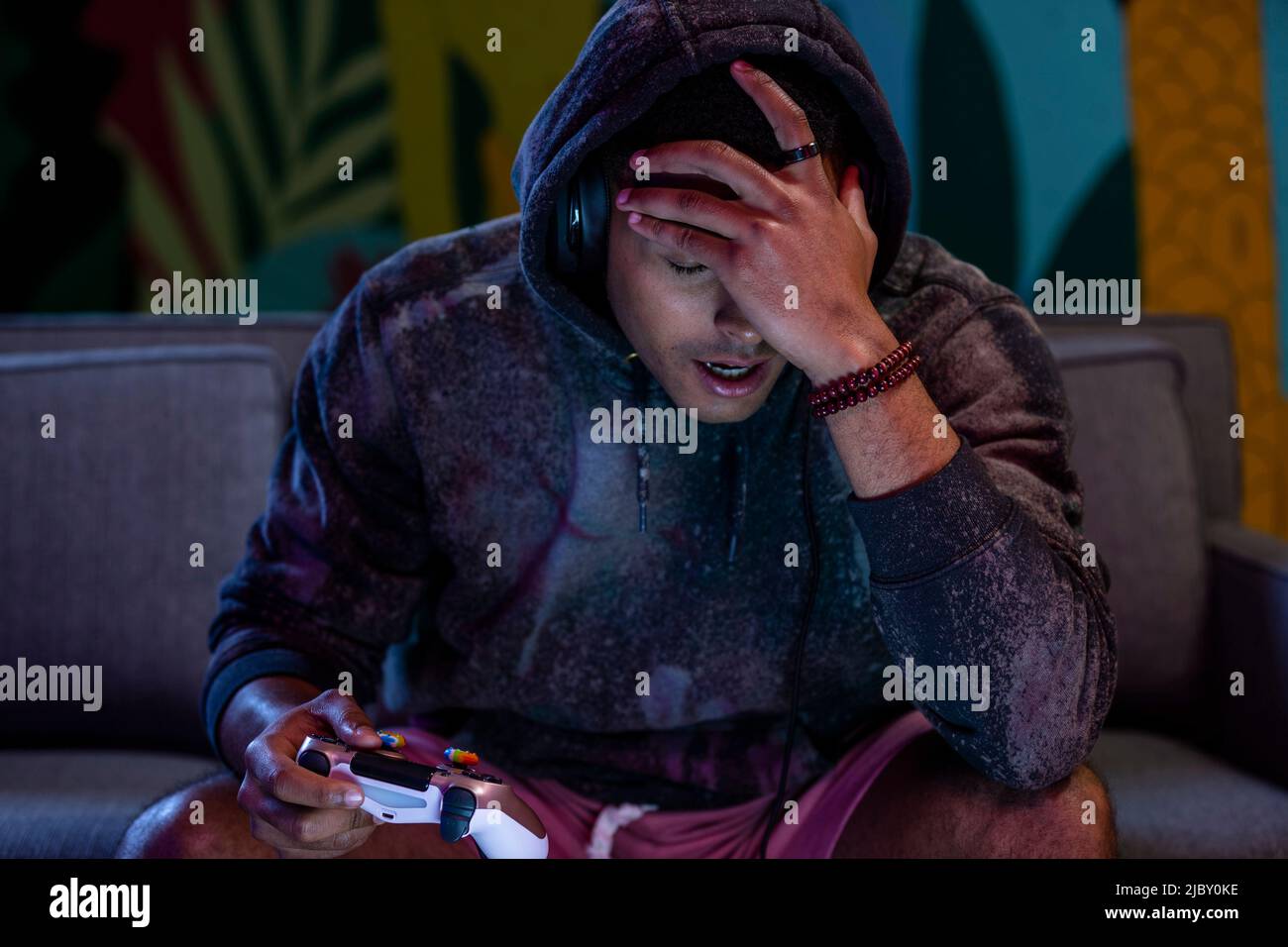 Jeune gamer masculin jouant à un jeu vidéo à la maison regardant la colère et frustré. Banque D'Images