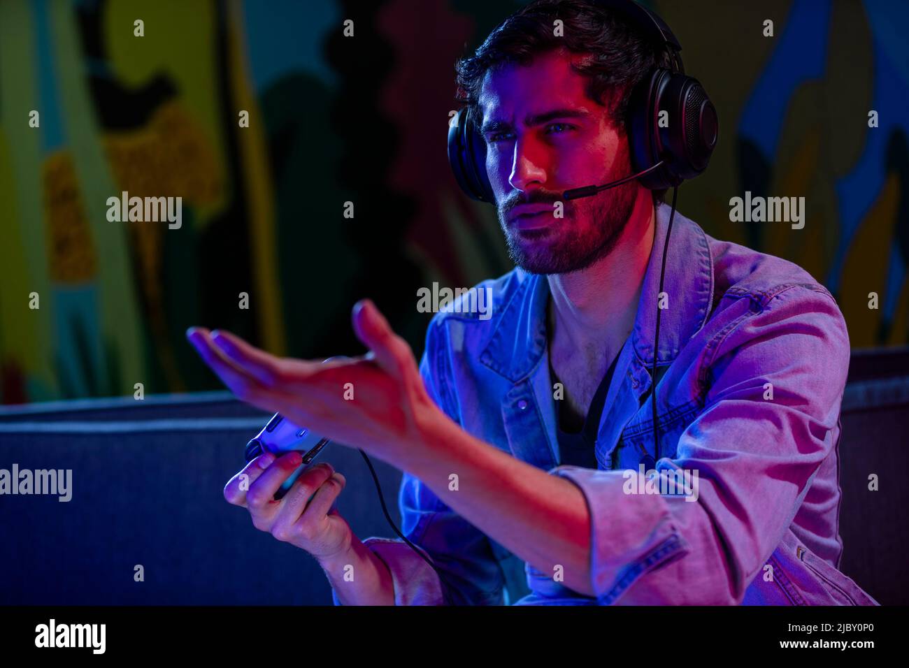 Un jeune homme en colère fait un geste à la télévision tout en jouant à un jeu vidéo. Banque D'Images