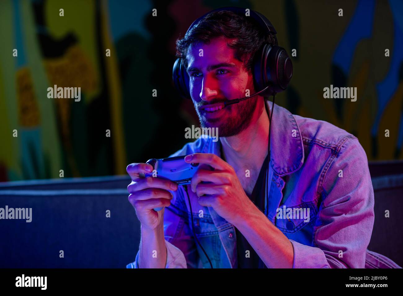 Lecteur de jeux vidéo dans sa chambre avec des lumières colorées et une manette de jeu. Banque D'Images