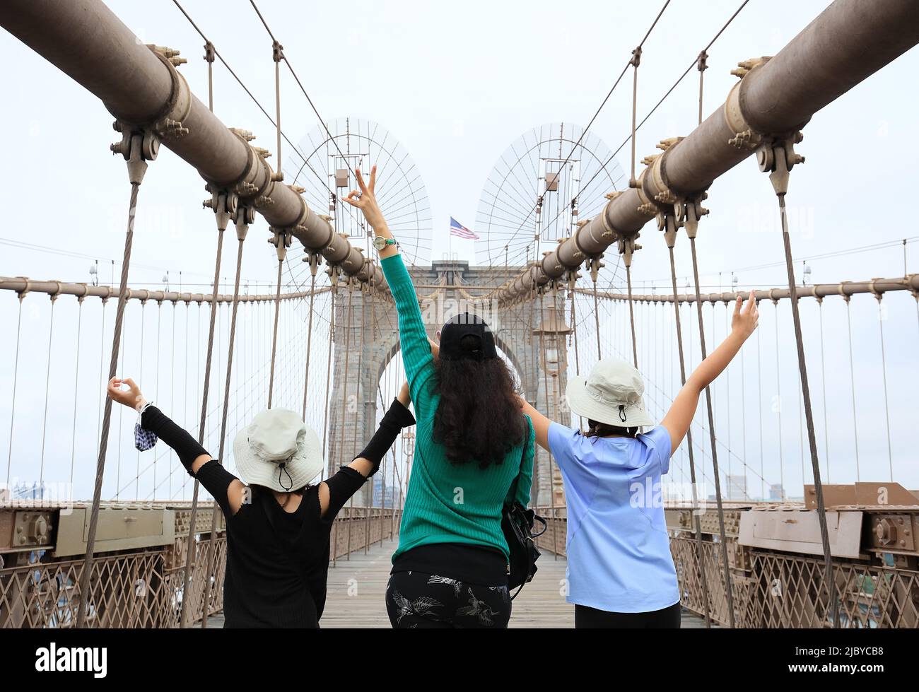 Mère et deux jeunes filles heureuses de visiter le pont de Brooklyn, mains levées montrant le signe de la victoire - Manhattan, New York, New York, Etats-Unis Banque D'Images
