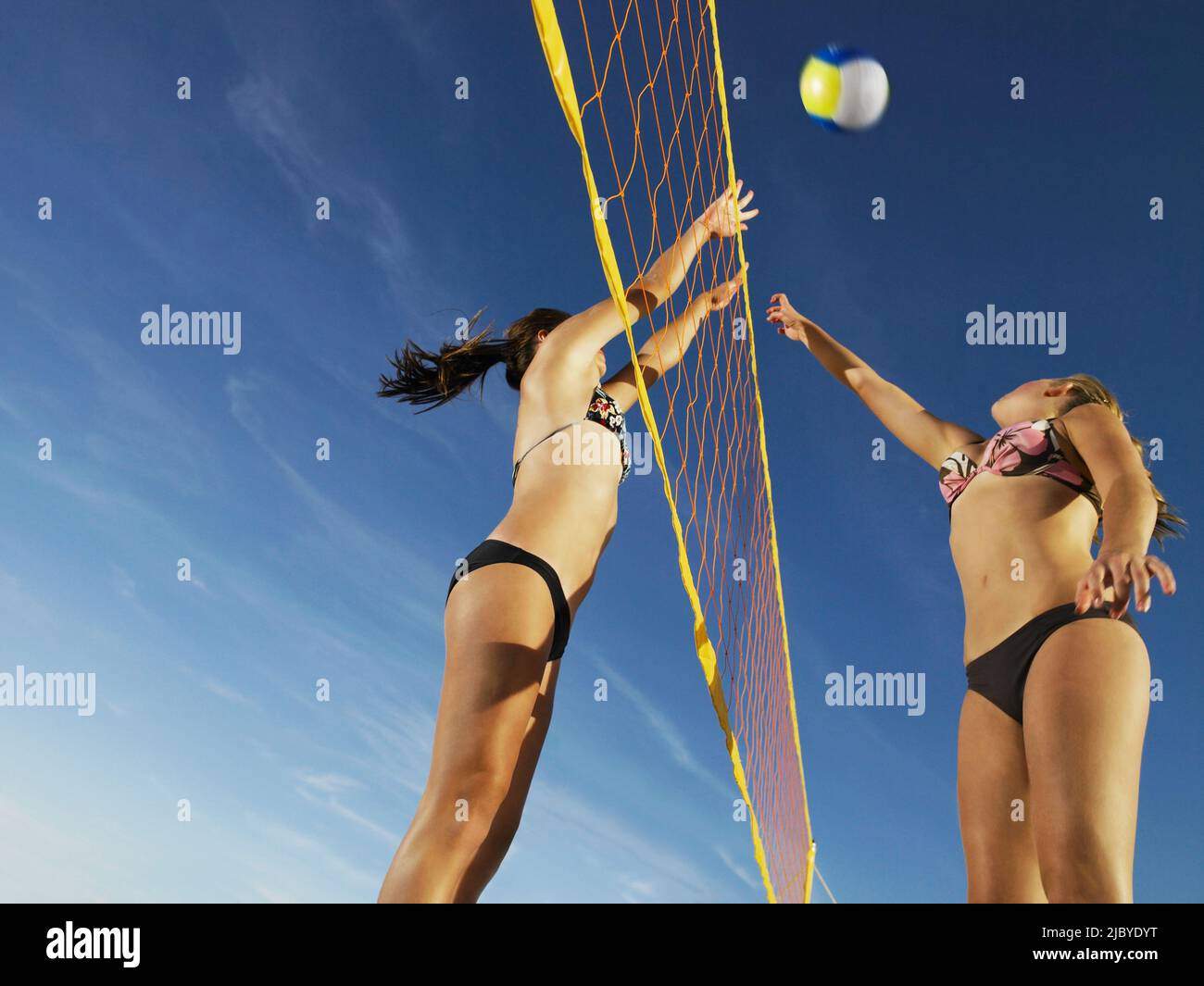 Deux femmes d'équipes opposées bondissant pour frapper le volley-ball sur le filet Banque D'Images