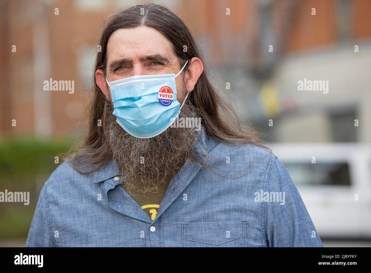Homme caucasien avec de longs cheveux et une barbe complète portant un masque et un autocollant J'ai voté aujourd'hui sur le masque, regardant dans l'appareil photo. Banque D'Images